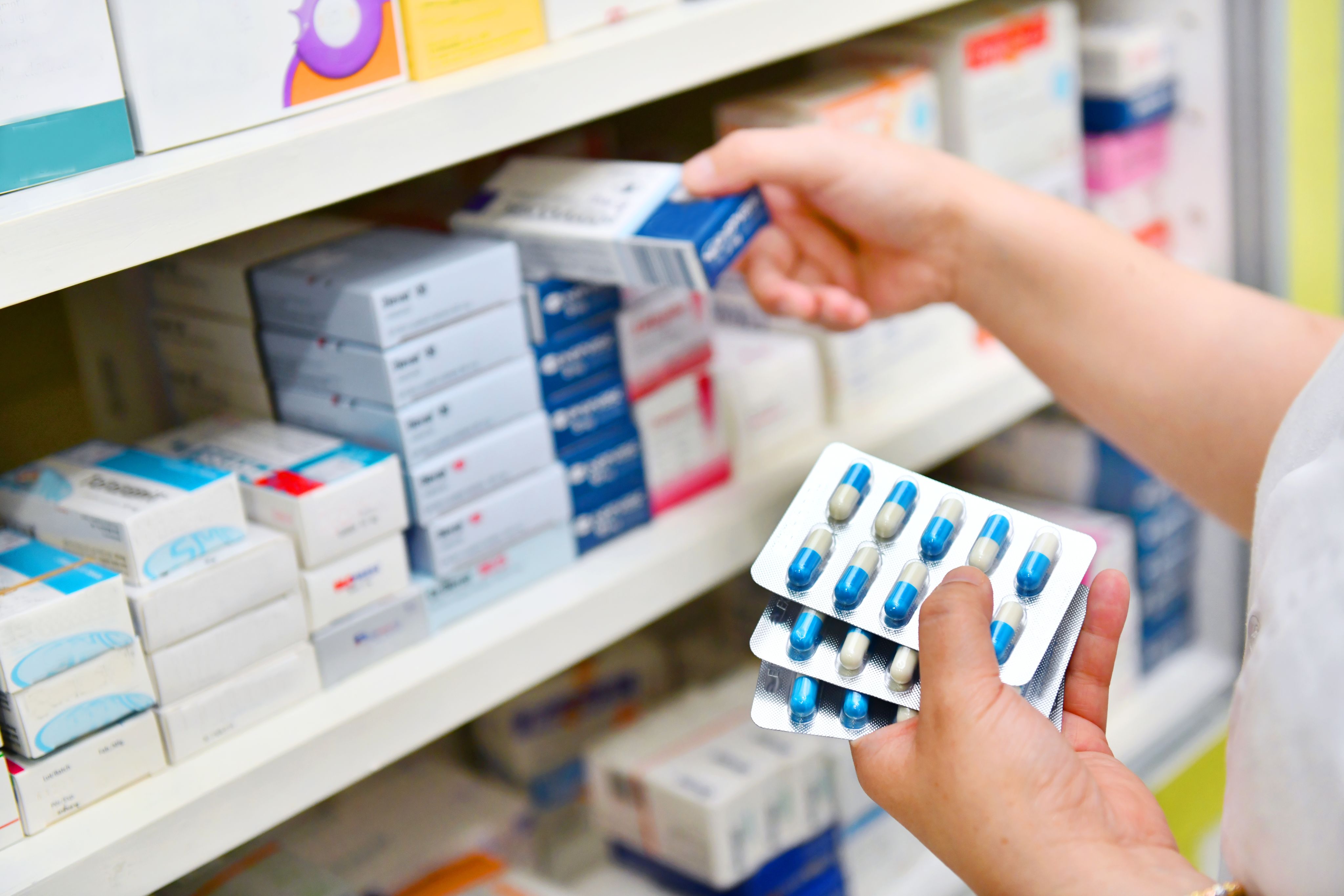 Pharmacist taking pills off a shelf
